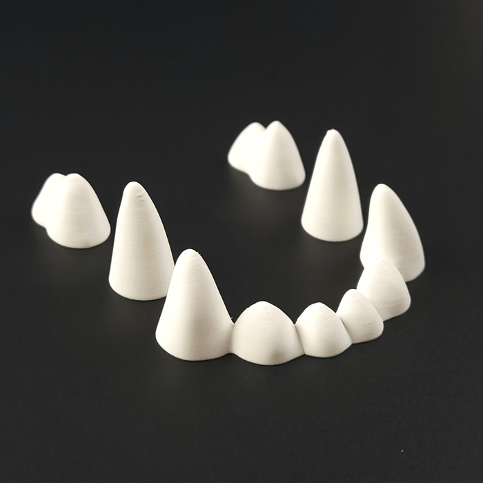Set of white 3D-printed pointed fursuit teeth arranged like an open mouth on a black background