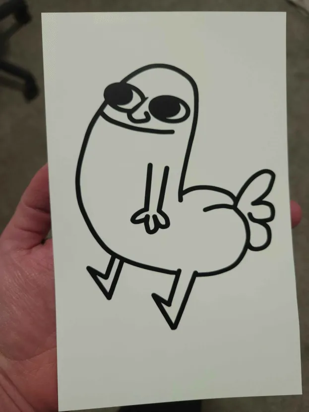 A completed black vinyl Dickbutt decal held in one hand, showing the smooth lines and clean cuts achieved. The finished decal was destined for my truck.